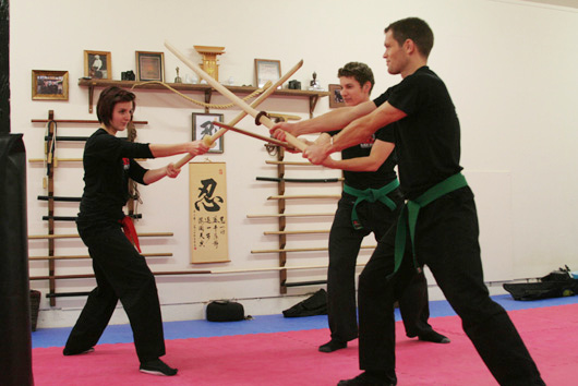 Weapons pair work with bokken and bo in front of the rack.
